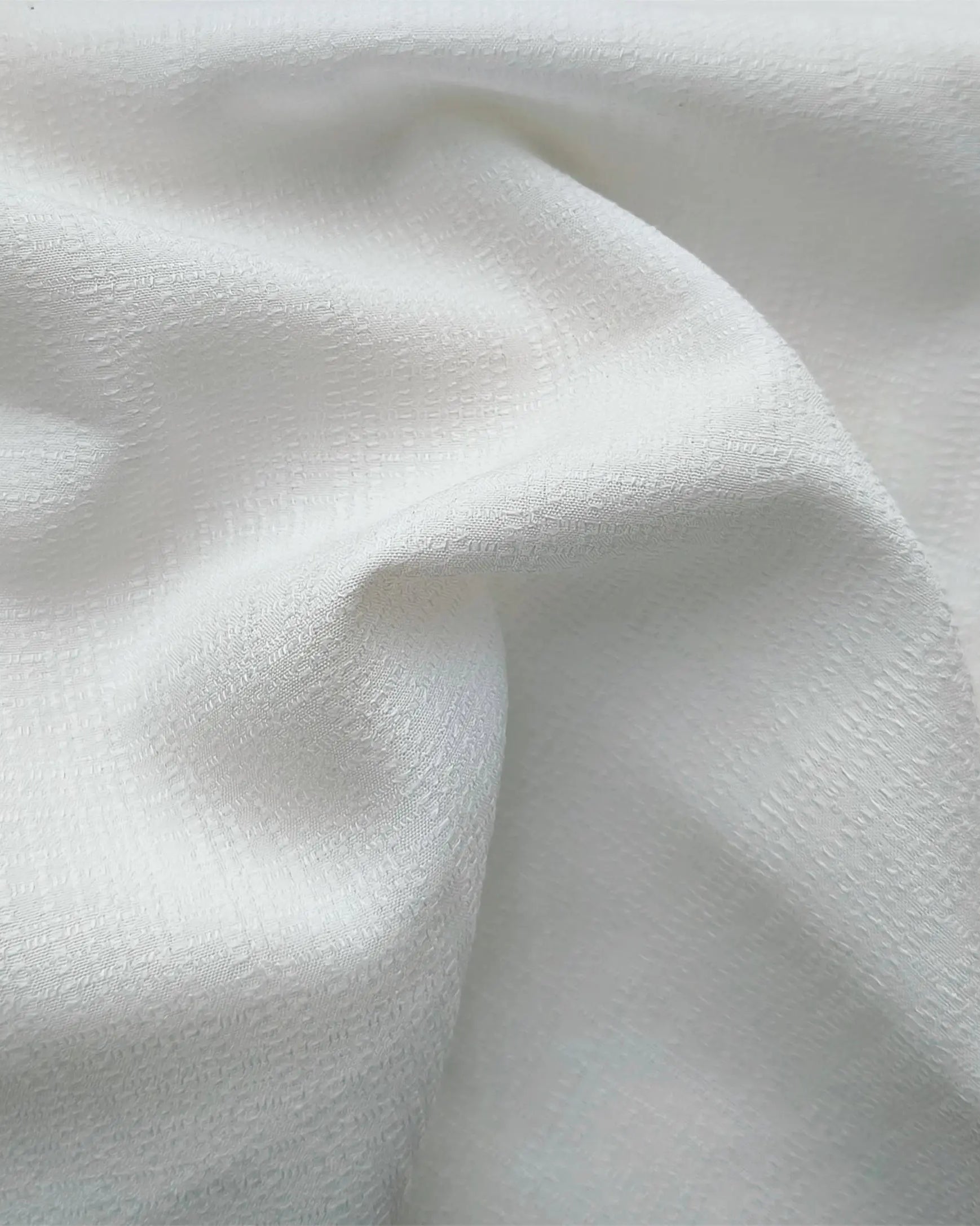 Grommet curtains made of white linen are installed on rods in the living room.