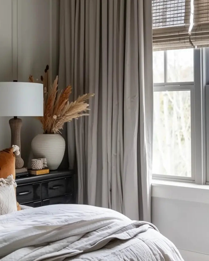 Simple solid gray curtains framing a window with natural light and bamboo blinds.