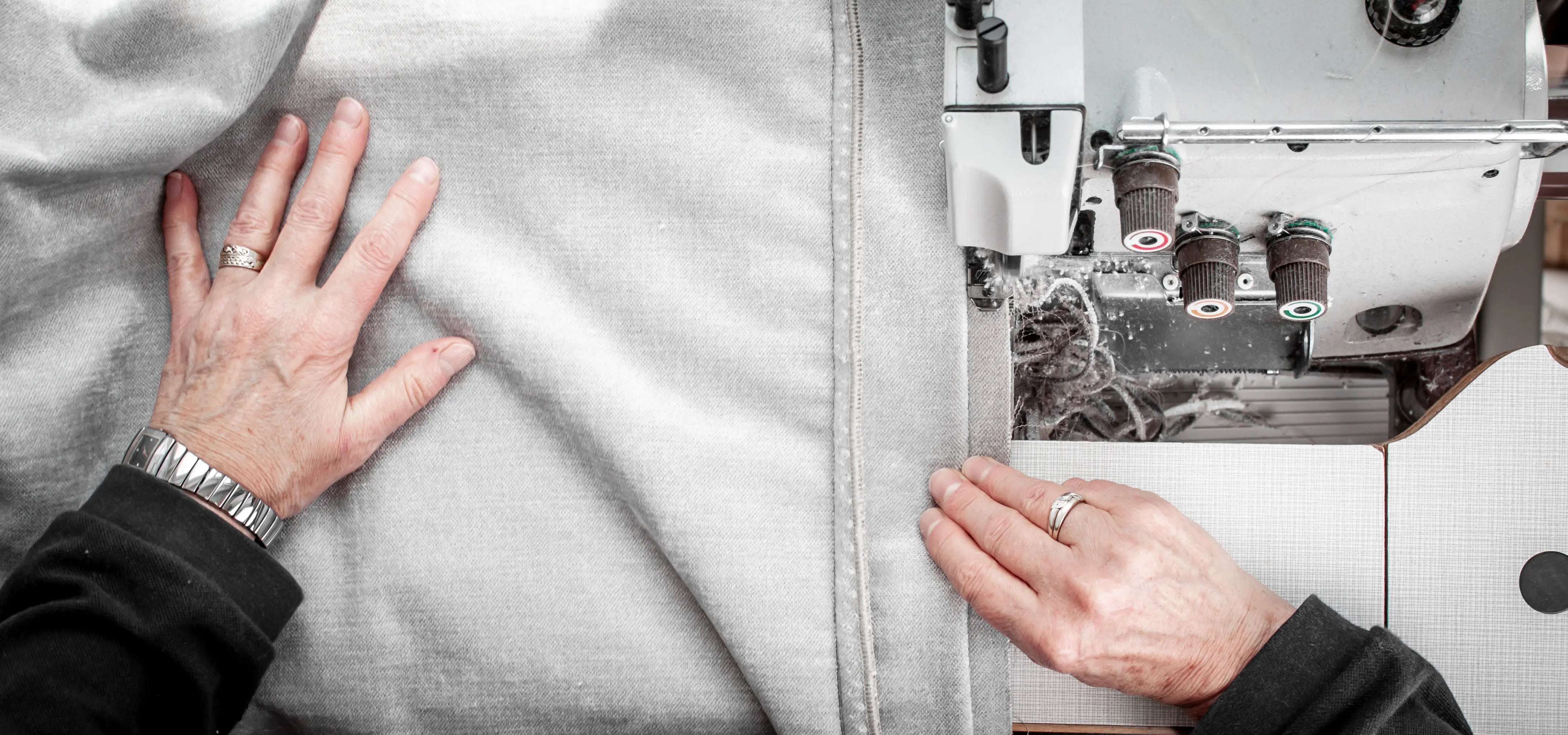 Tailor working on a sewing machine with fabric, focusing on precise stitching